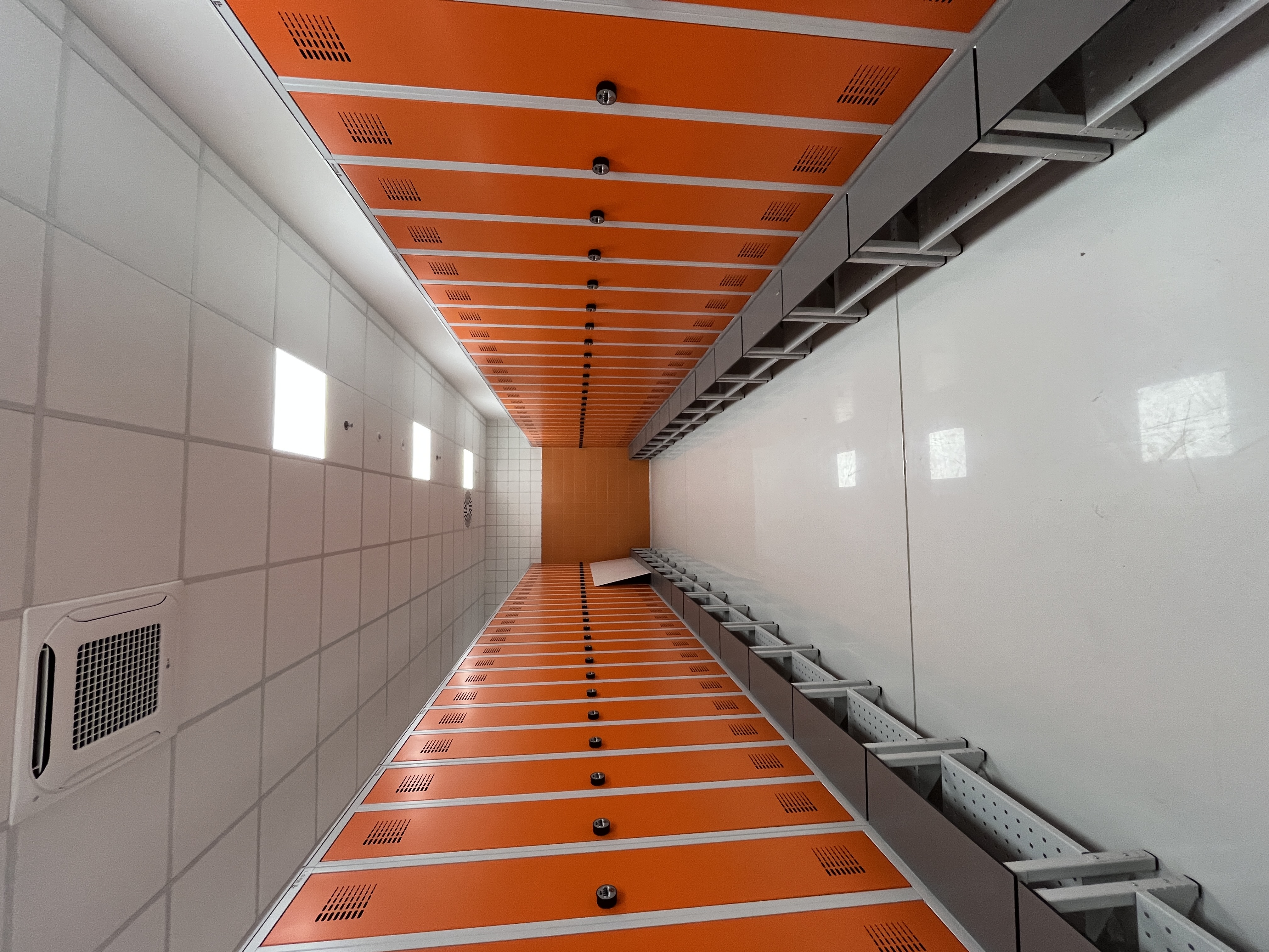 Metalowe szafy ubraniowe SUM 420 W ST z siedziskiem HPL i półką na buty, daszek, zamek szyfrowy (tryb prywatny), korpus RAL 7035, front RAL 2004 – realizacja Pozmebel Niepruszewo